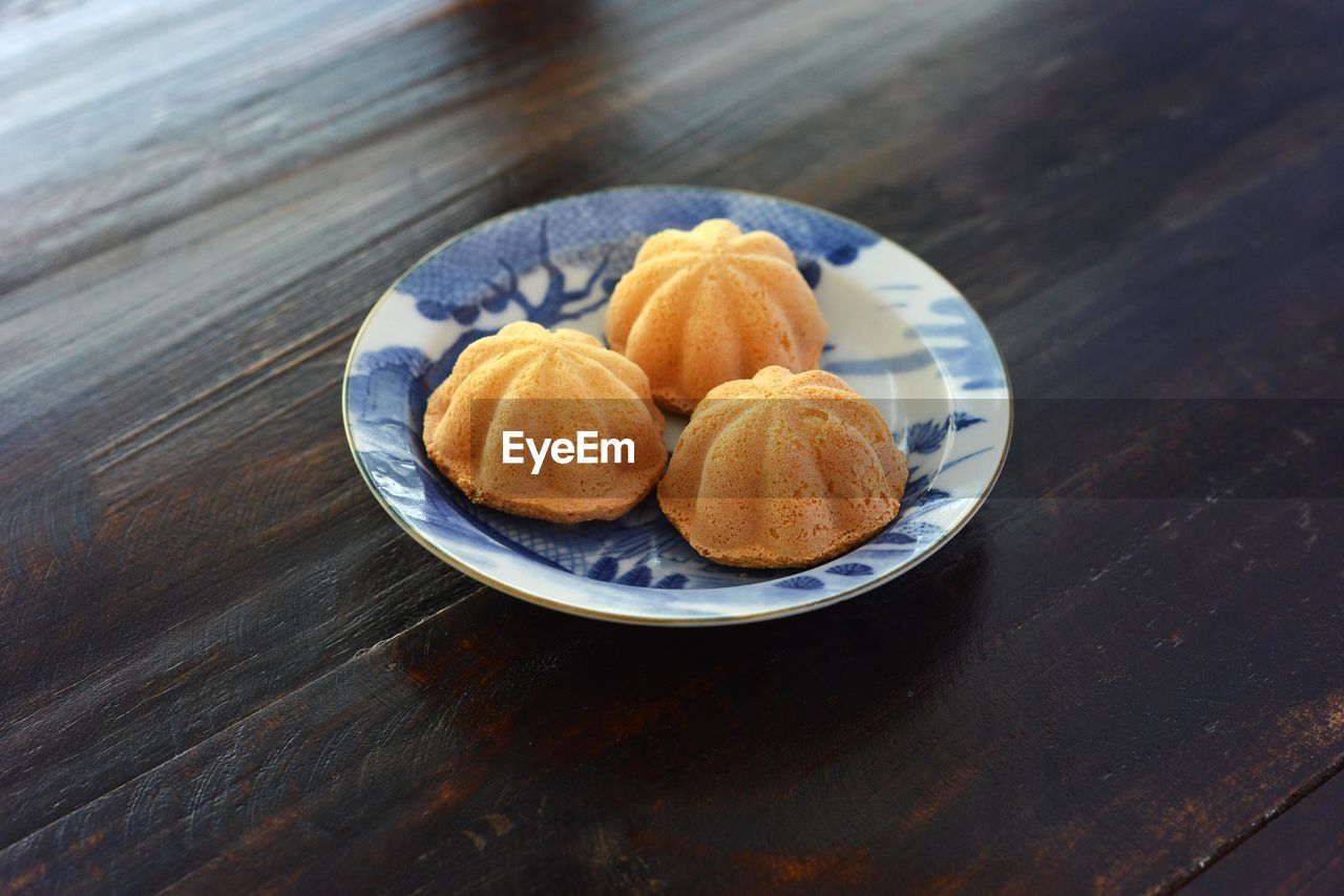 High angle view of kuih bahulu in plate on wooden table