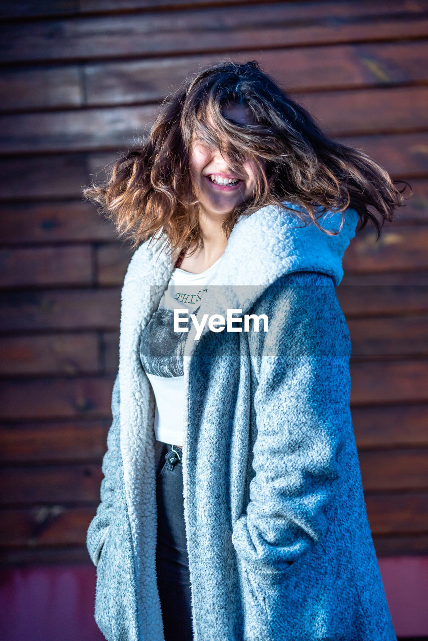 PORTRAIT OF A SMILING WOMAN STANDING IN WINTER