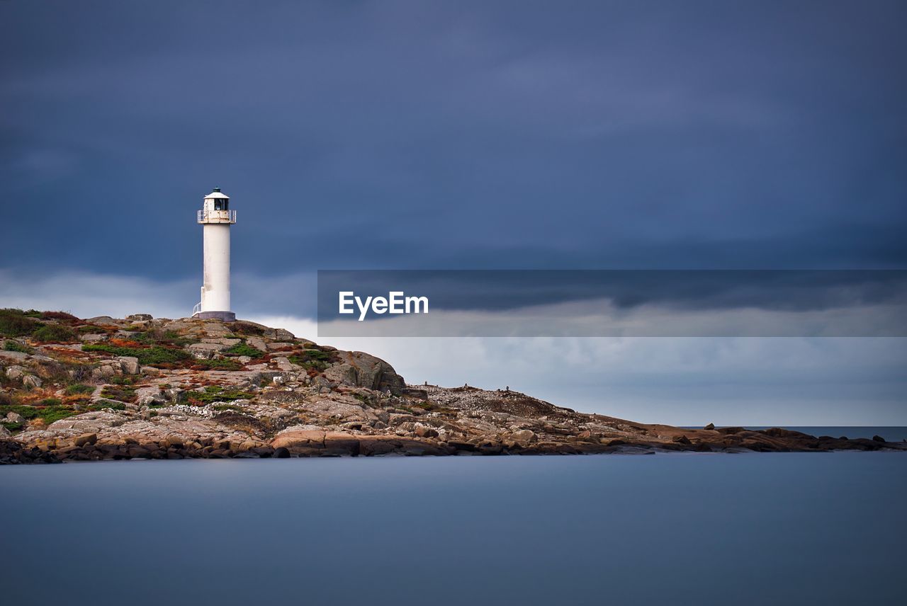 Lighthouse by sea against sky