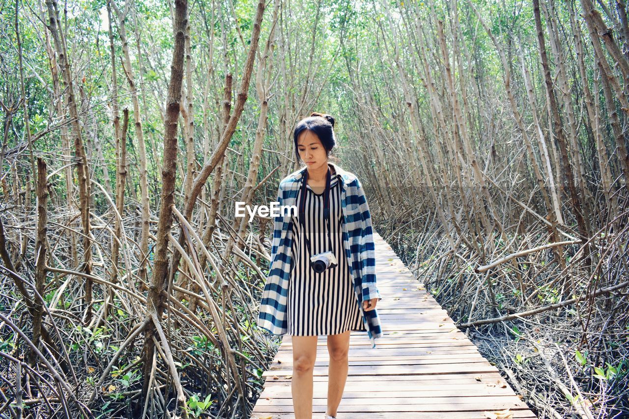 Woman standing on footbridge in forest
