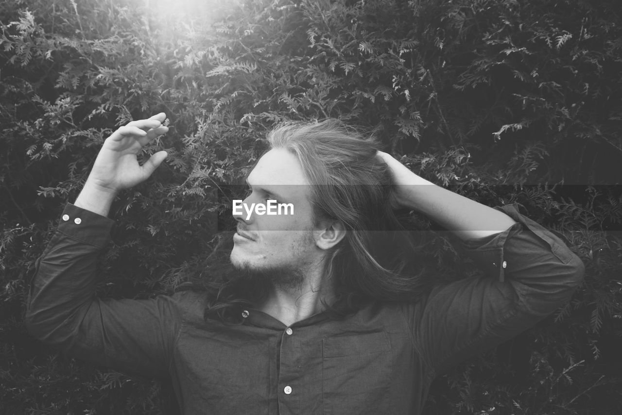 Young man with hand hair standing by plants