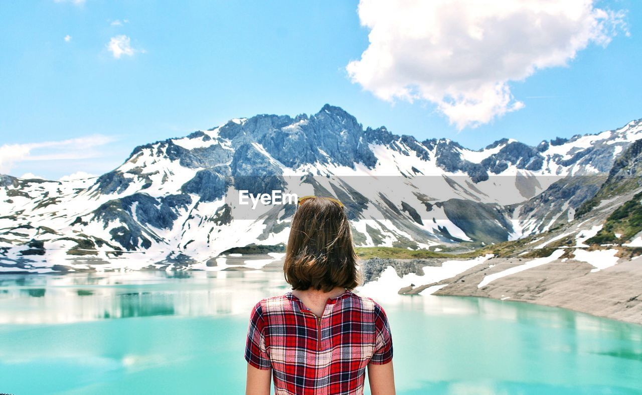 Rear view of woman looking at lake against mountain