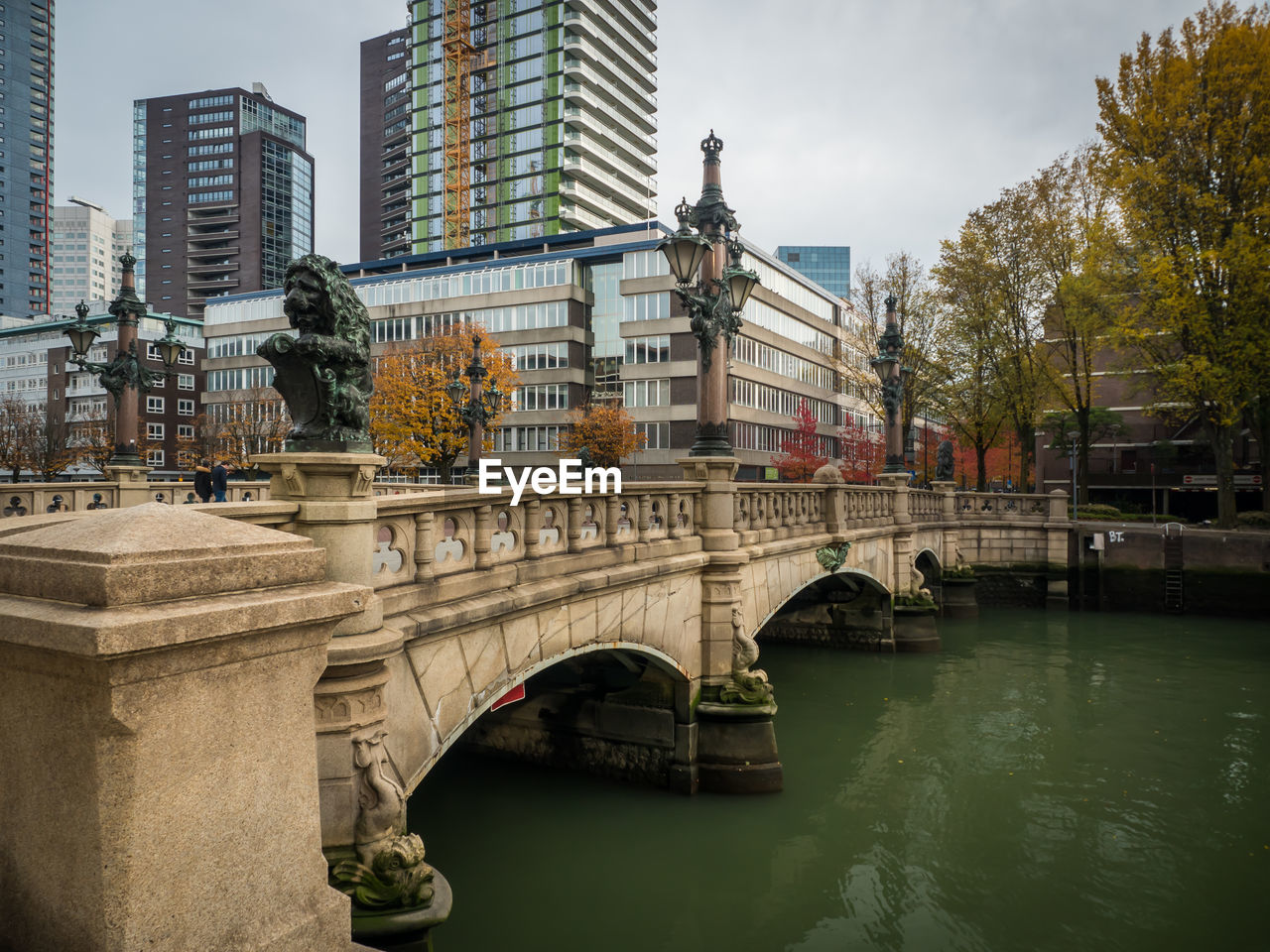 Arch bridge over river by buildings against sky