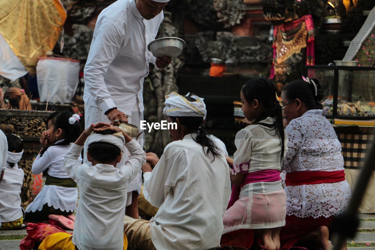 REAR VIEW OF PEOPLE ENJOYING IN TEMPLE