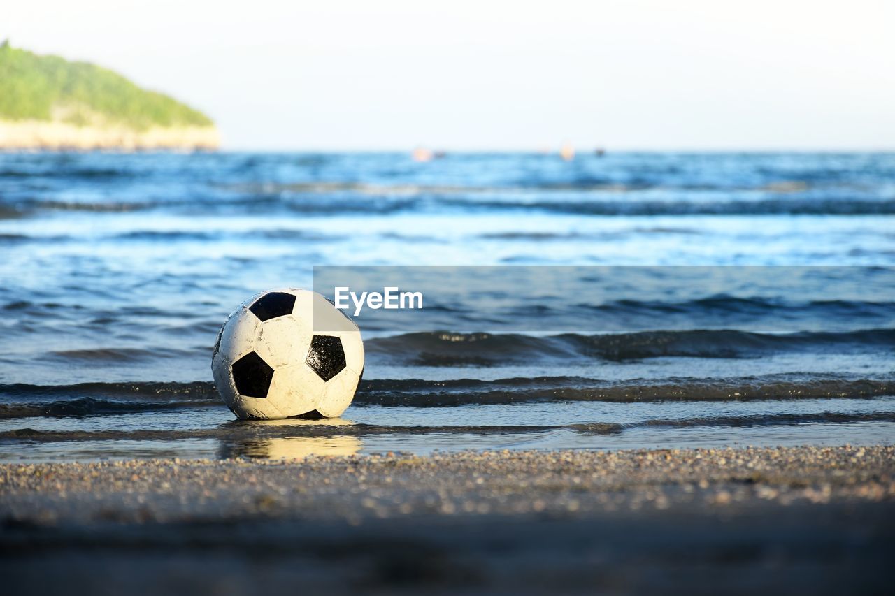 Soccer ball floating in the sea and hit the waves on the beach.