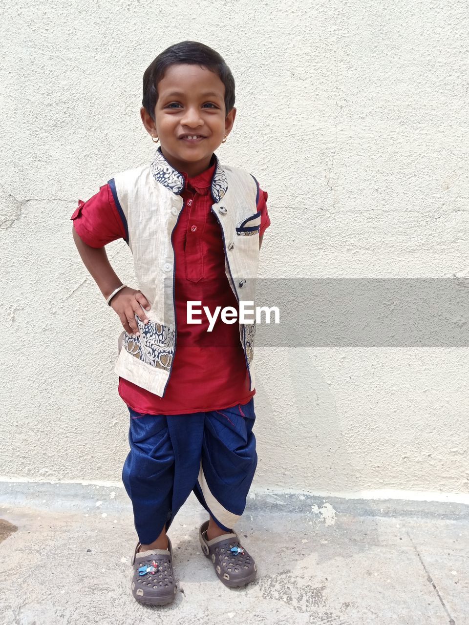 one person, child, childhood, portrait, smiling, looking at camera, full length, men, standing, happiness, emotion, architecture, front view, wall - building feature, casual clothing, spring, lifestyles, person, red, clothing, cheerful, day, cute, smile, teeth, footwear, leisure activity, student