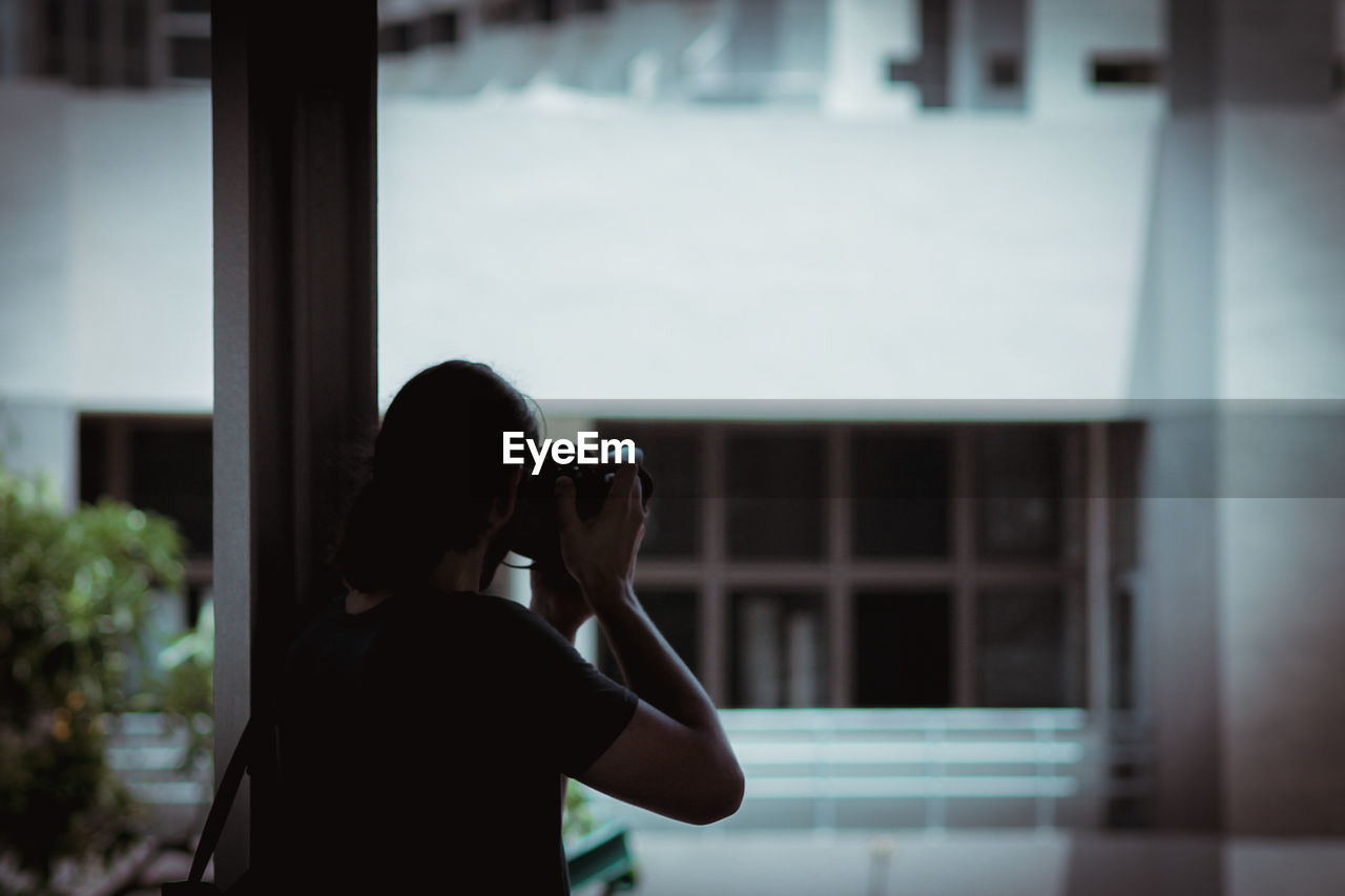 Close-up of woman photographing against building