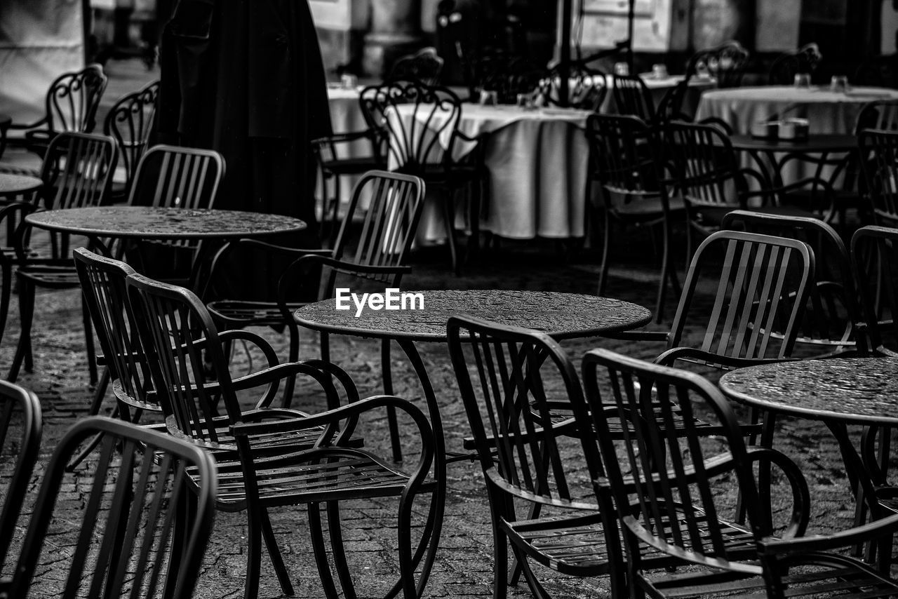 Empty chairs and tables at sidewalk coffee shop