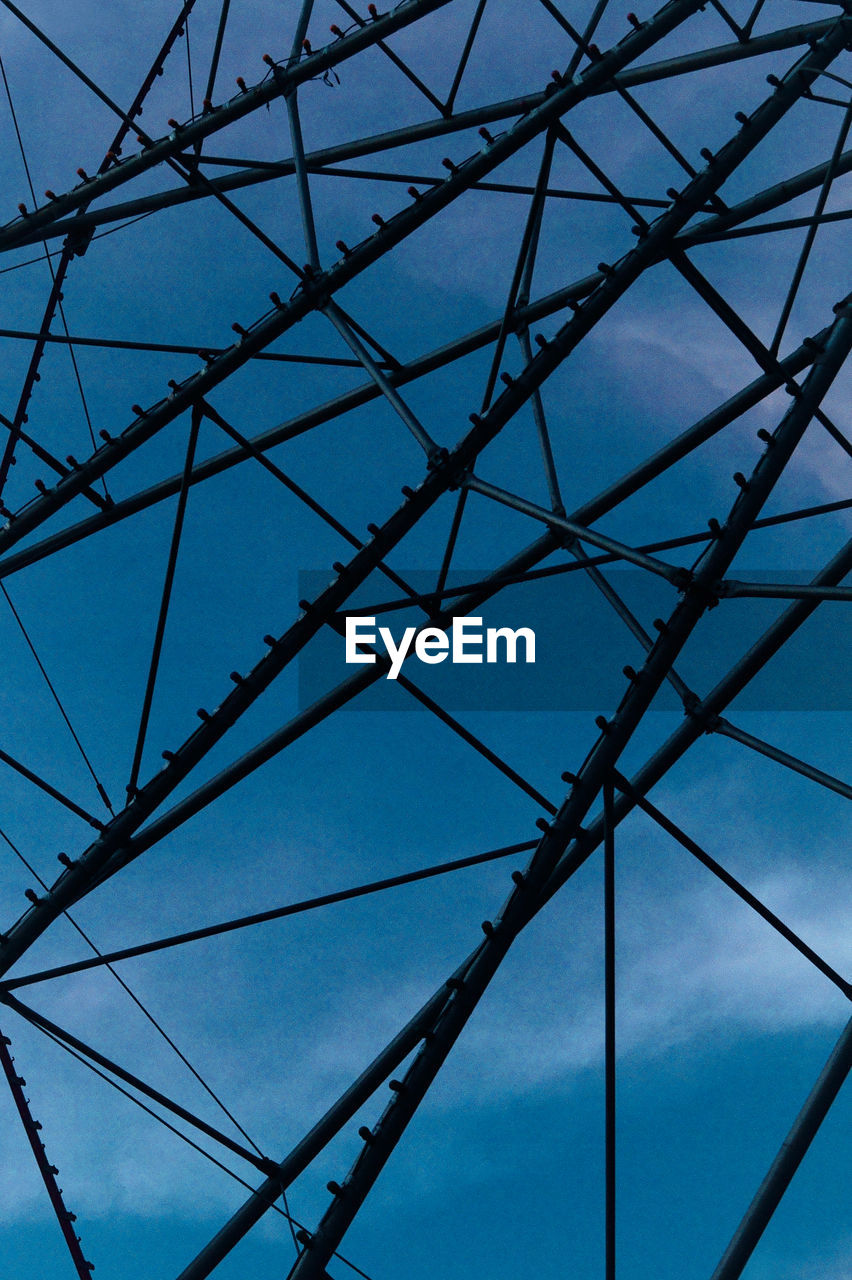 Low angle view of electricity pylon against blue sky