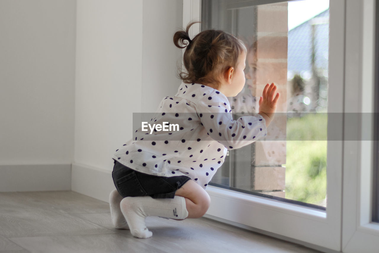 Little girl with ponytails looks out the window. new home rental.