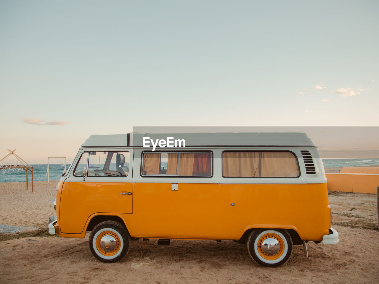 Vintage van at beach against sky during sunset