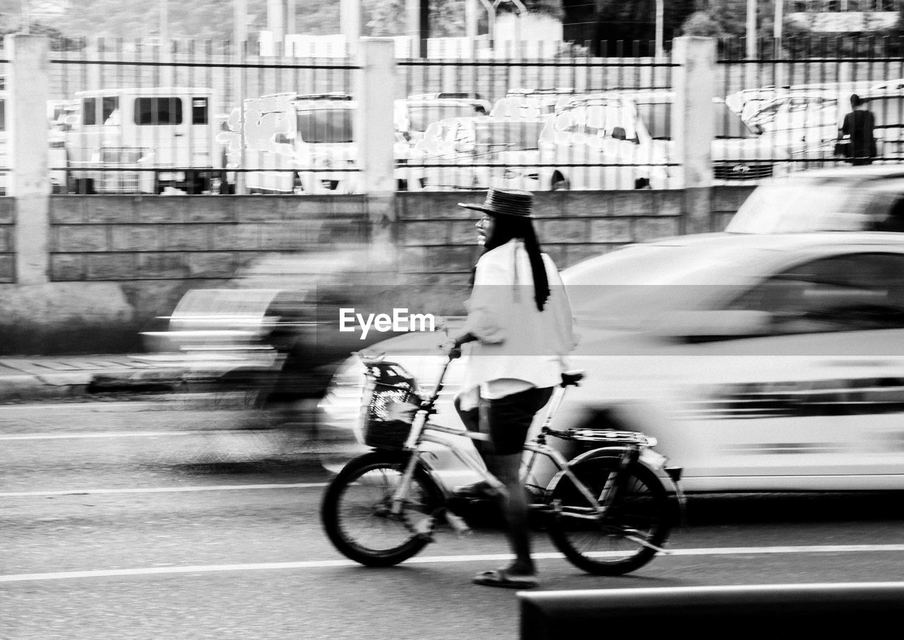 WOMAN RIDING BICYCLE ON ROAD