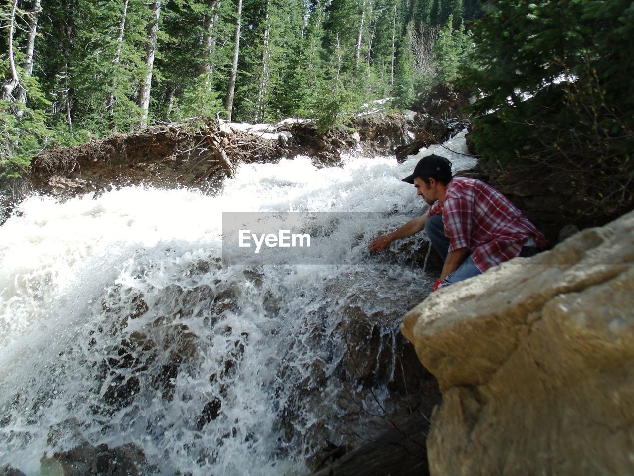 Man sitting by waterfall in forest