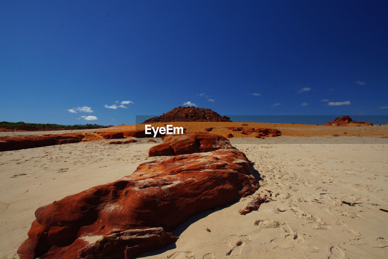 ROCK FORMATIONS ON SAND AGAINST SKY