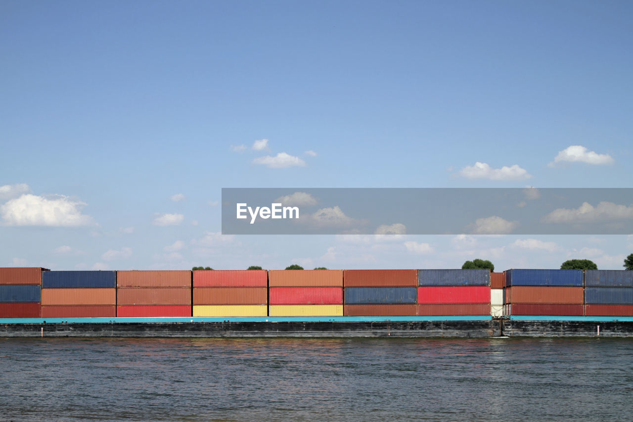 Cargo ship with numerous colorful containers on a river