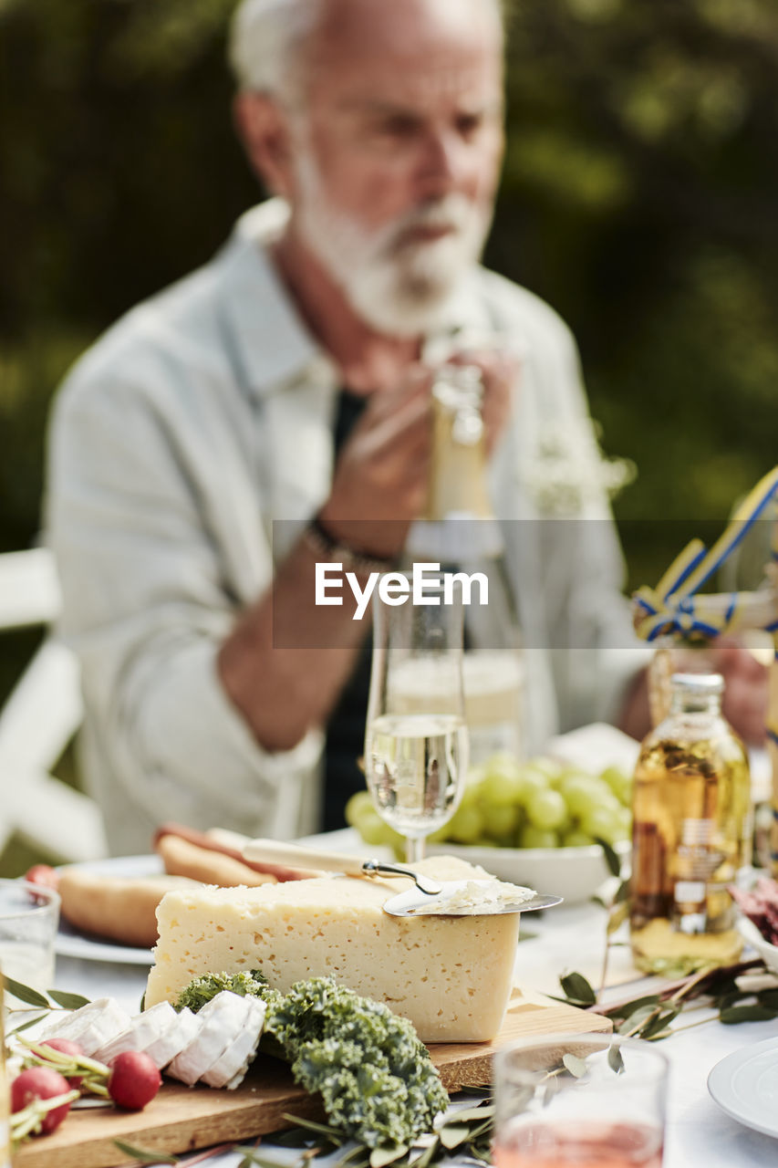 Cheese on wooden board, man on background