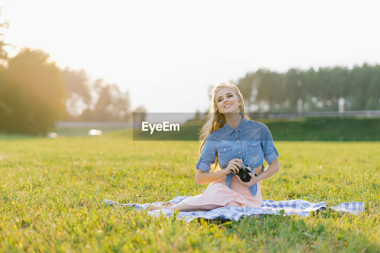 Attractive young woman with a camera in her hands is resting and taking pictures outdoors person