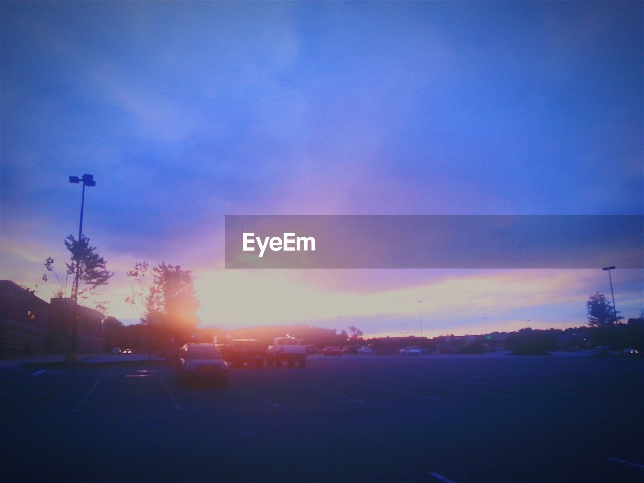 Cars on road against cloudy sky during sunset