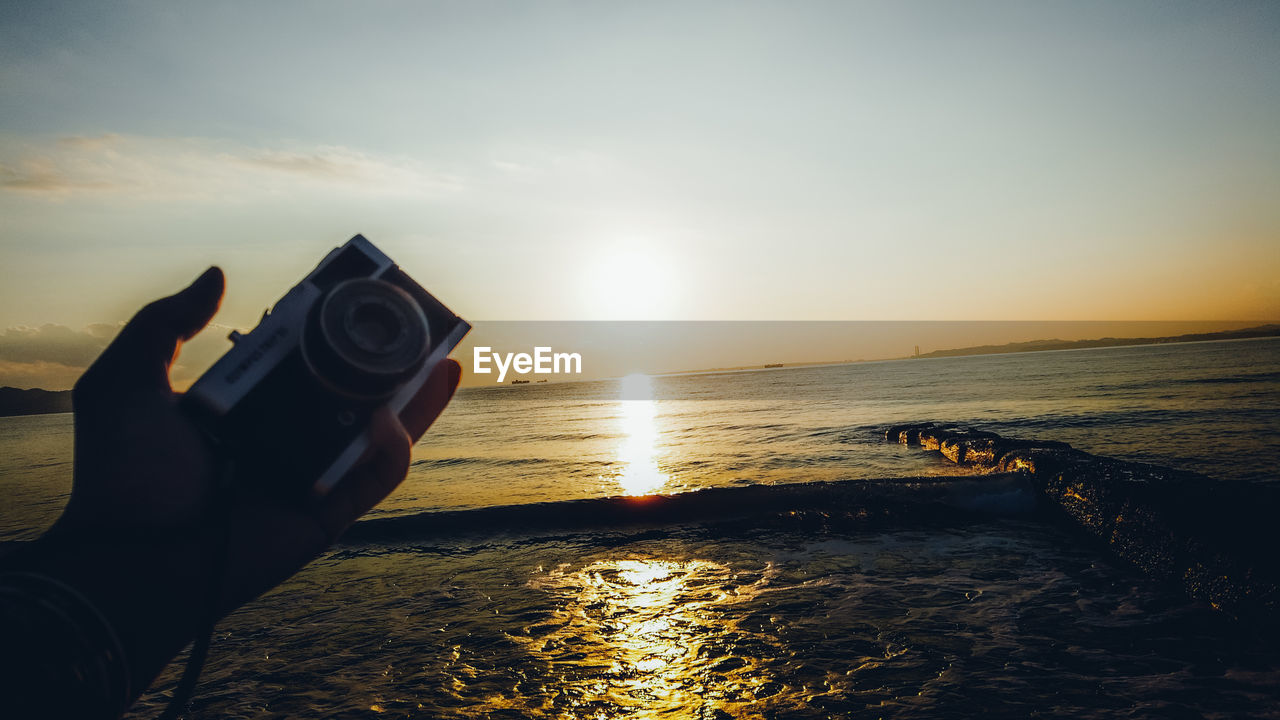 PERSON HOLDING SUN OVER SEA