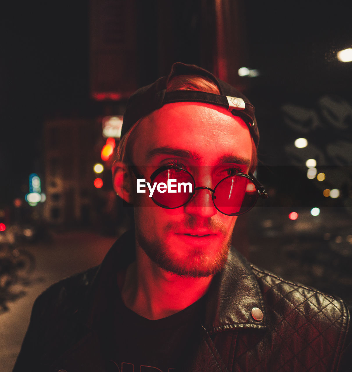 Young man wearing eyeglasses in illuminated city at night