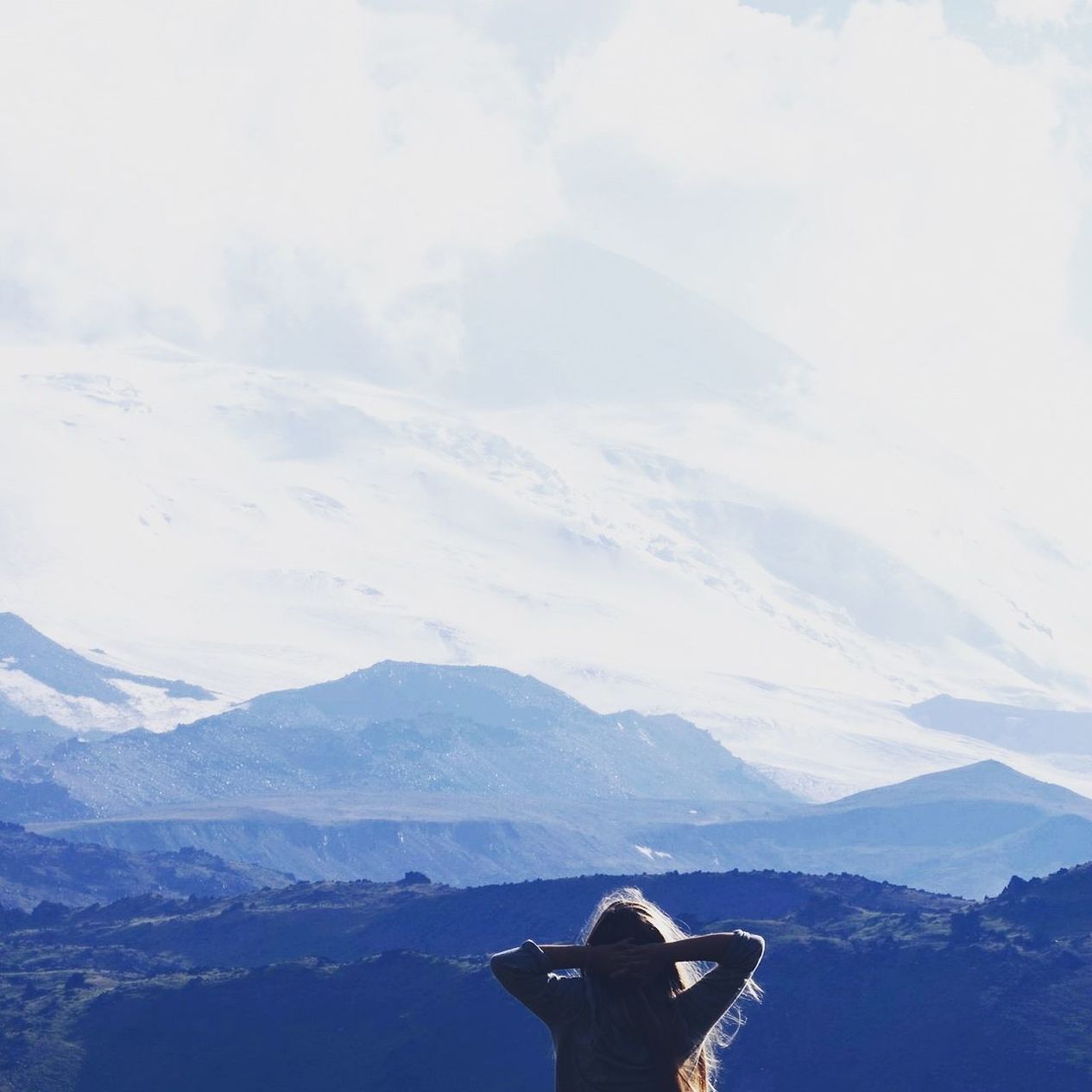 REAR VIEW OF MAN STANDING ON SNOW COVERED MOUNTAIN