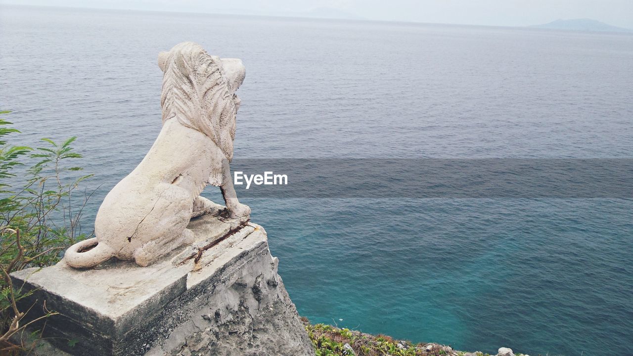 Lion statue against sea