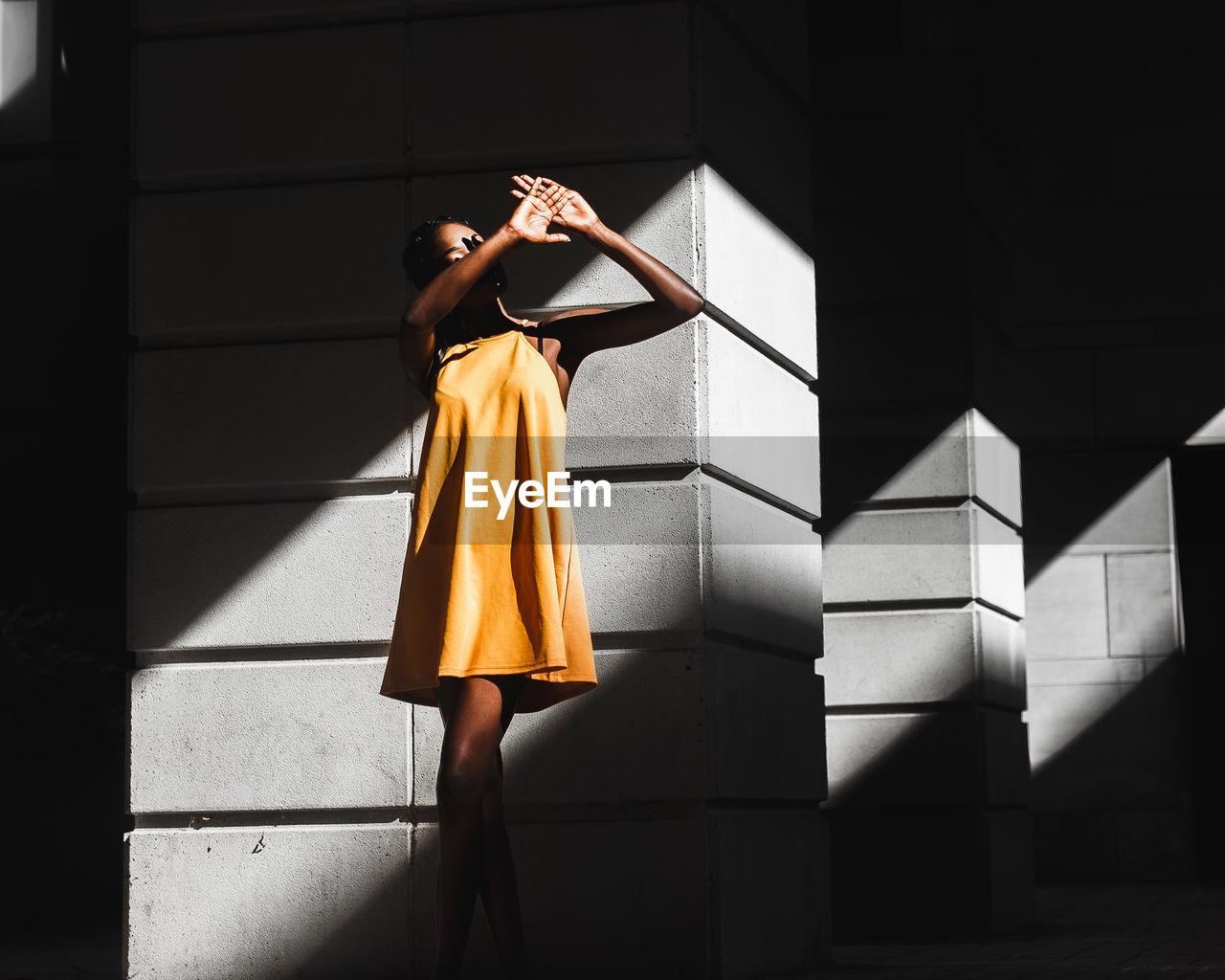 YOUNG WOMAN STANDING WITH YELLOW UMBRELLA