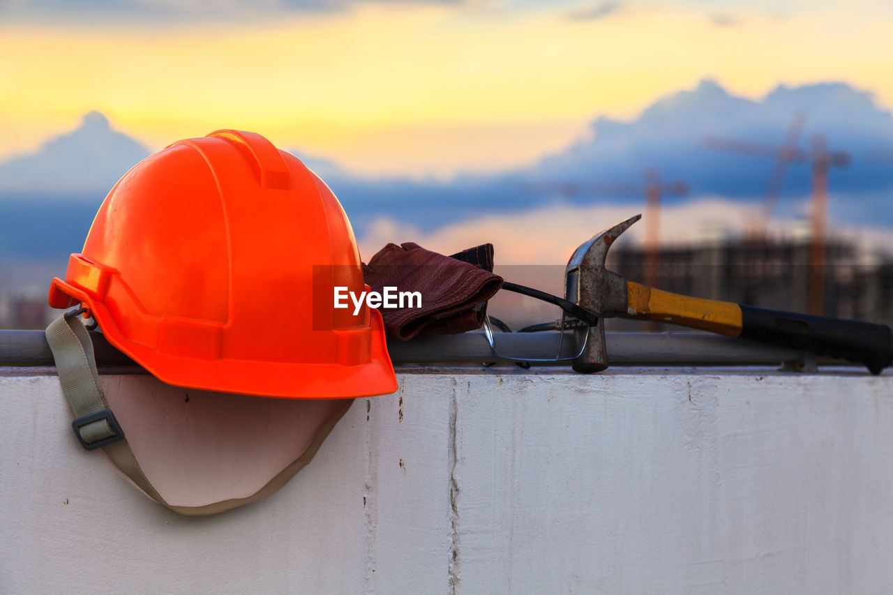 Helmet and hammer on retaining wall at sunset