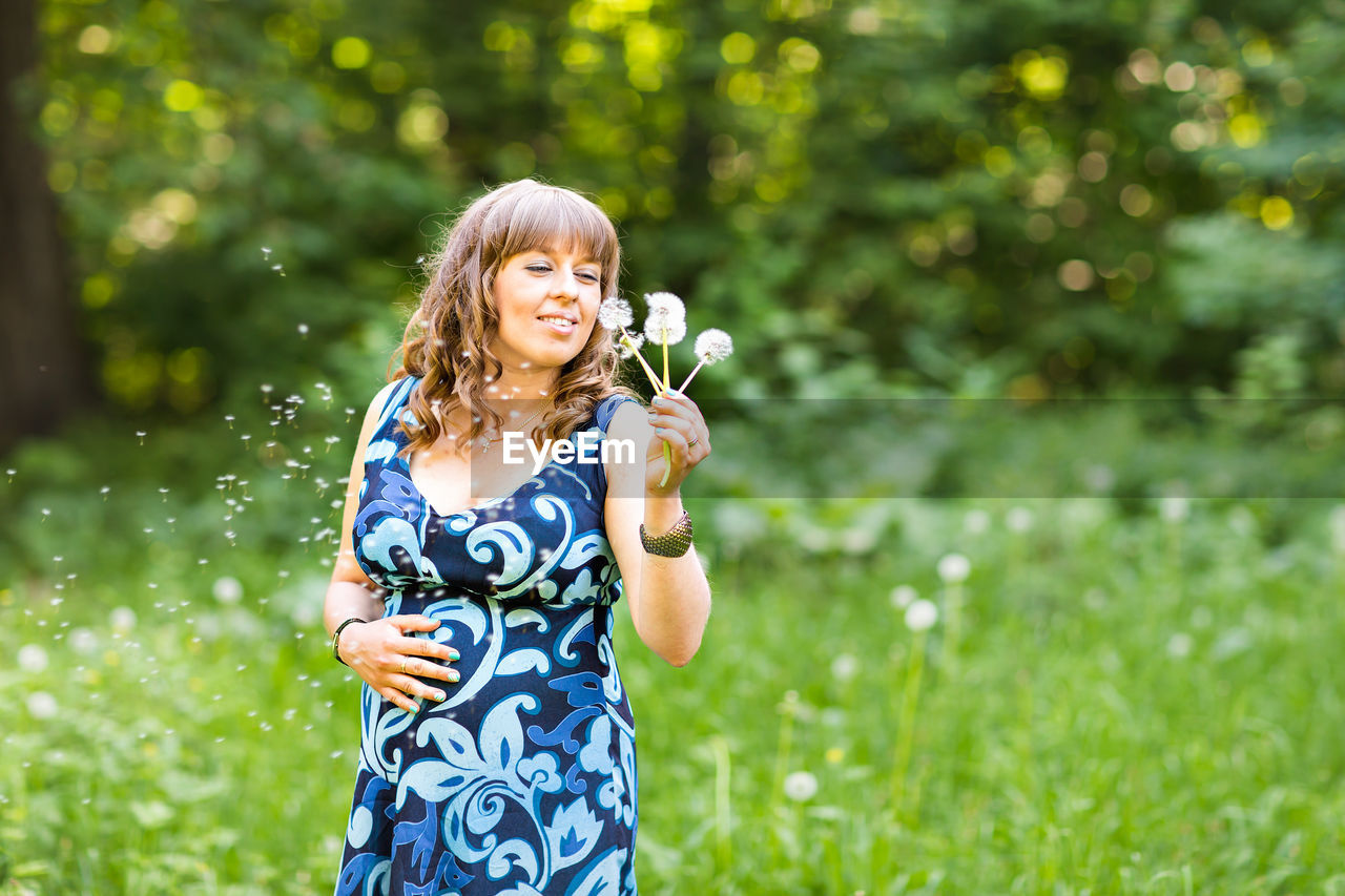 Woman holding flower while standing on field