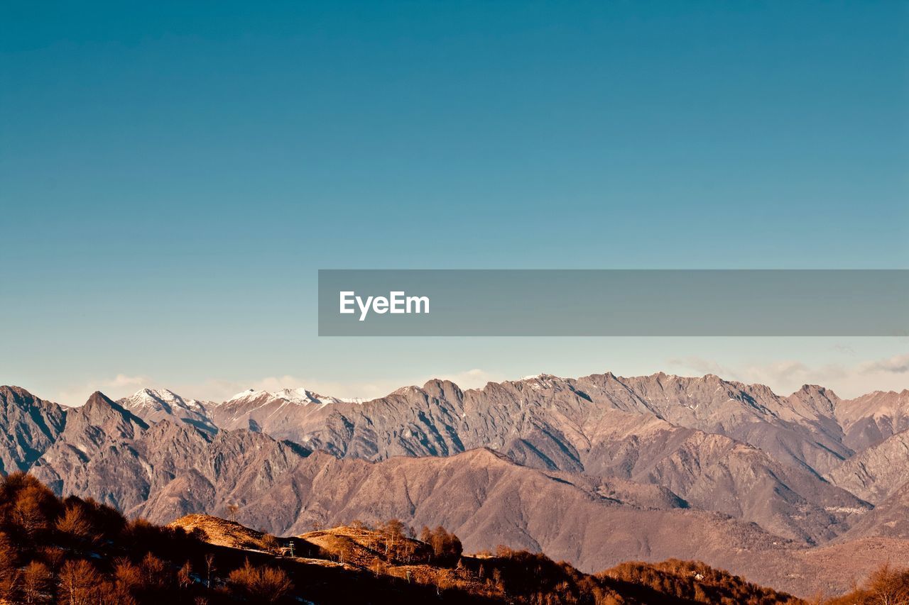 Scenic view of snowcapped mountains against clear blue sky