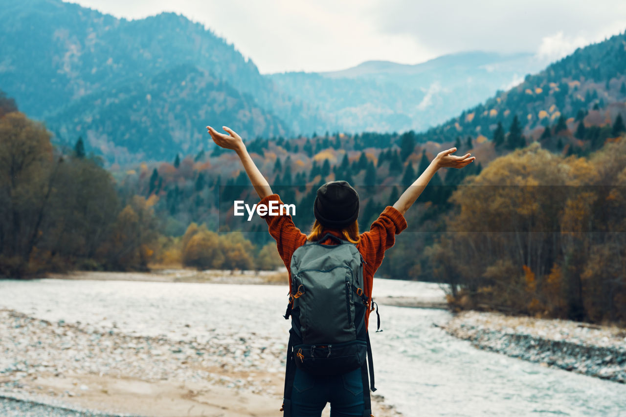 REAR VIEW OF MAN STANDING ON MOUNTAIN