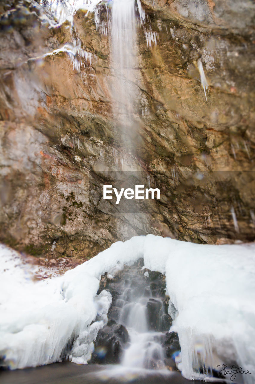 CLOSE-UP OF WATERFALL ALONG SNOW COVERED LANDSCAPE
