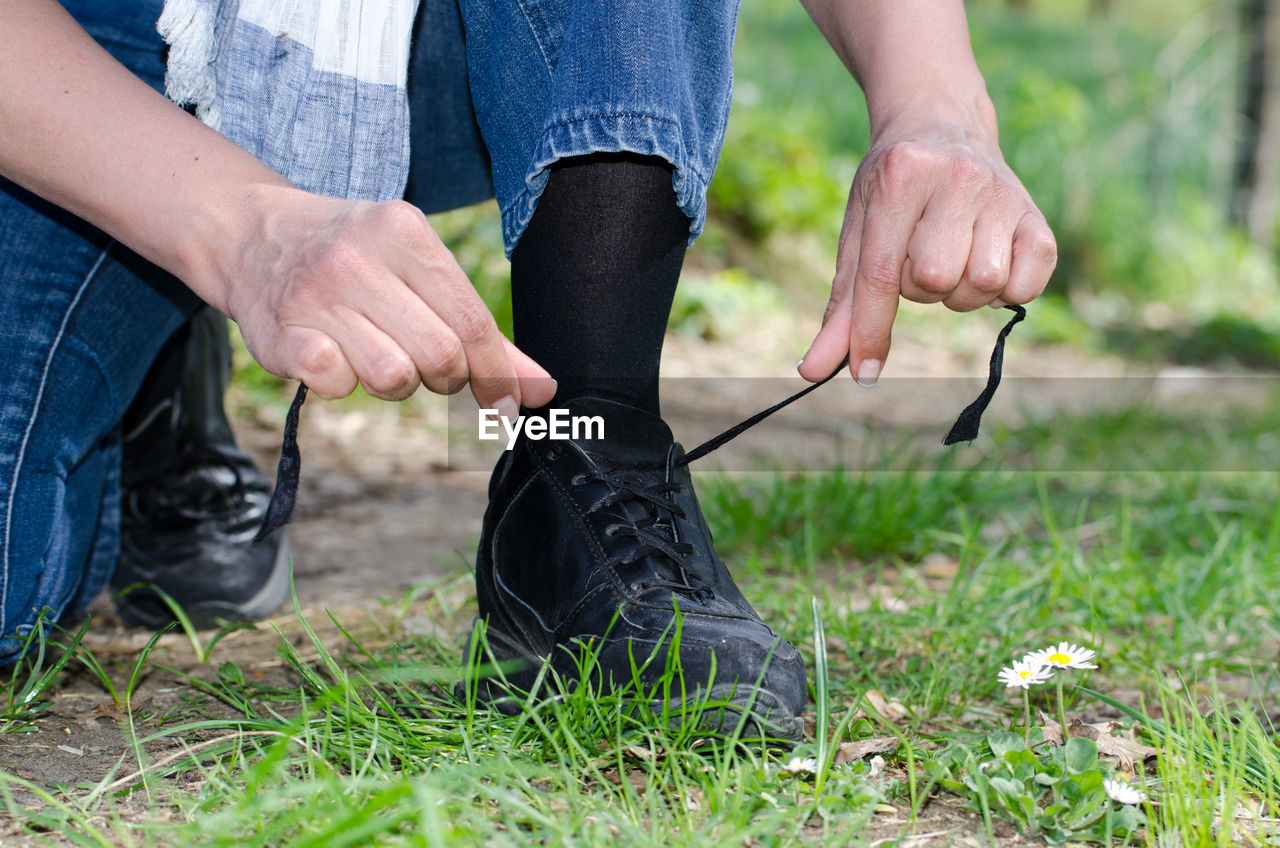 Low section of woman tying shoelaces on grass