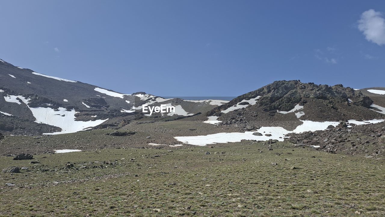 snow, mountain, environment, cold temperature, scenics - nature, sky, landscape, winter, beauty in nature, mountain range, ridge, snowcapped mountain, nature, plateau, no people, tranquility, wilderness, tranquil scene, mountain pass, day, non-urban scene, travel, land, travel destinations, outdoors, cloud, blue, summit, idyllic, tourism, adventure