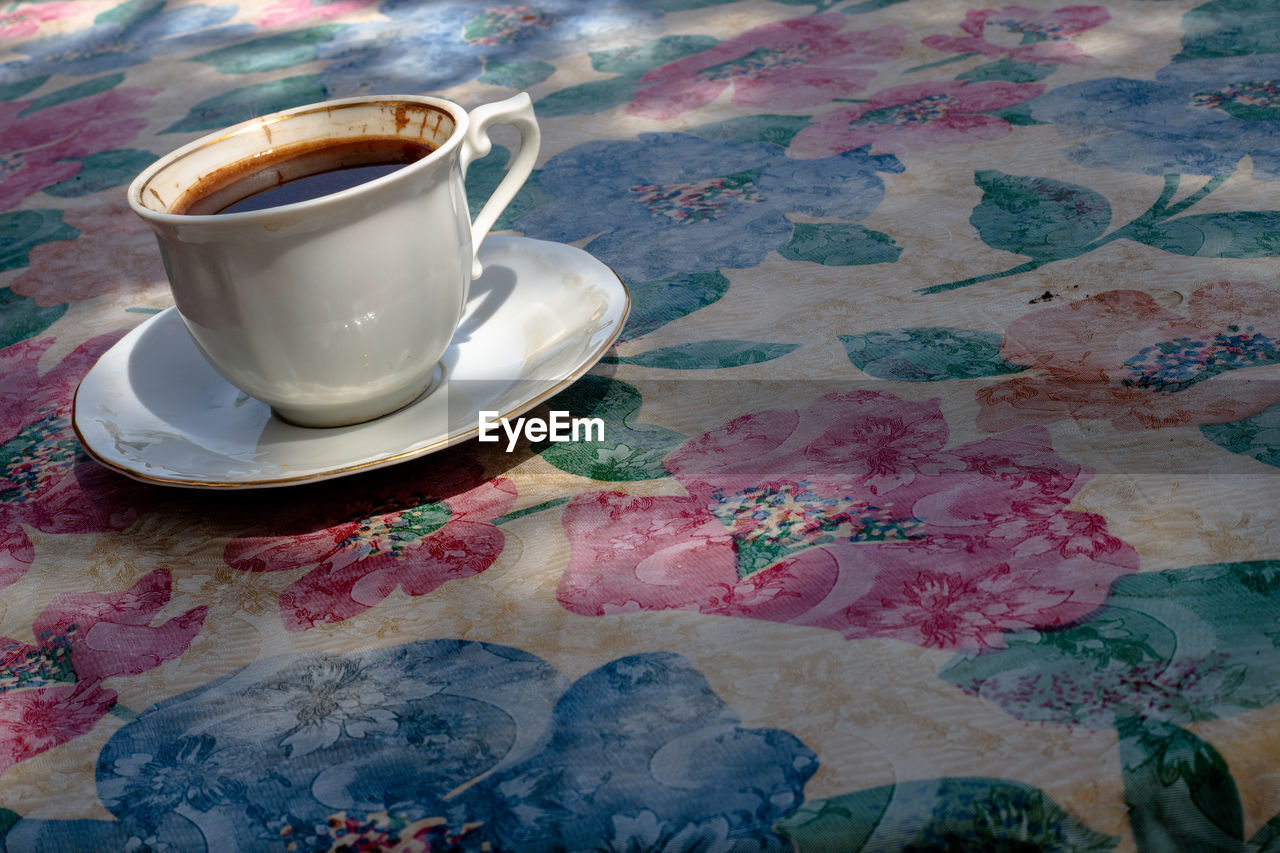 CLOSE-UP OF COFFEE CUP ON TABLE AGAINST BLACK BACKGROUND