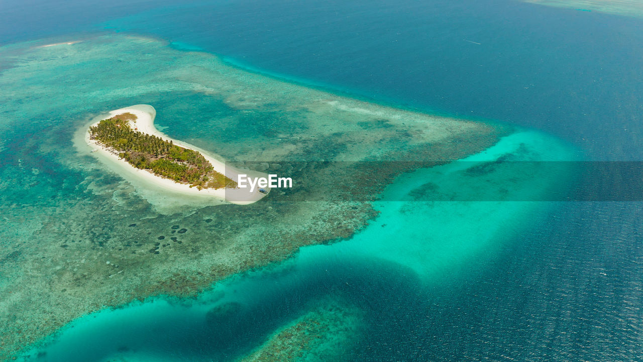 Tropical island on an atoll with beautiful sandy beach by coral reef.canimeran island and coral reef
