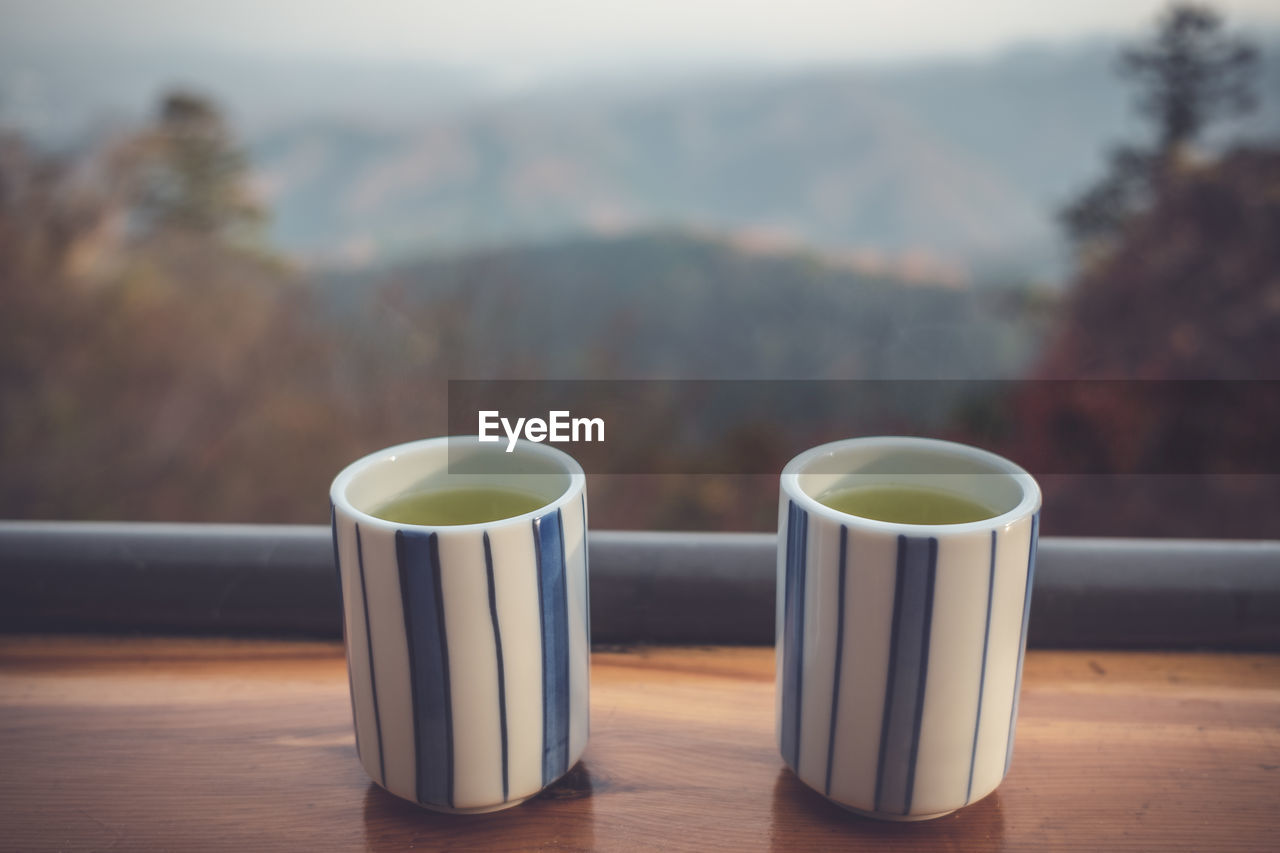 CLOSE-UP OF COFFEE CUP ON TABLE AGAINST BLURRED BACKGROUND