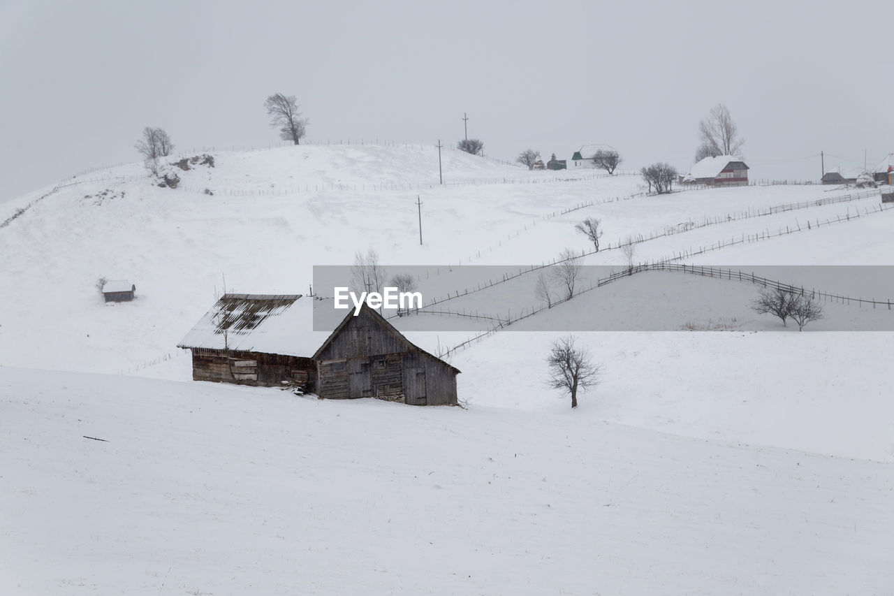 Houses on snow covered landscape against sky