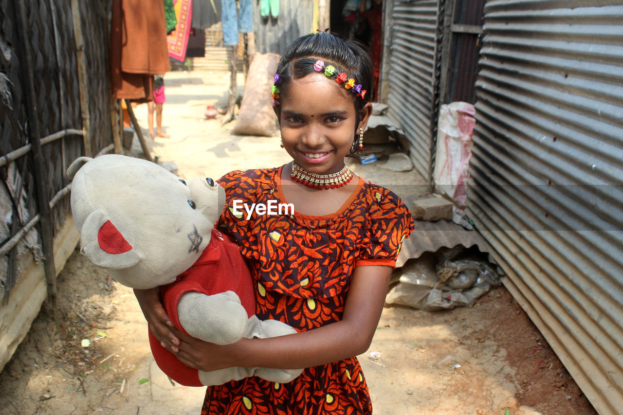 Portrait of a smiling young girl holding doll