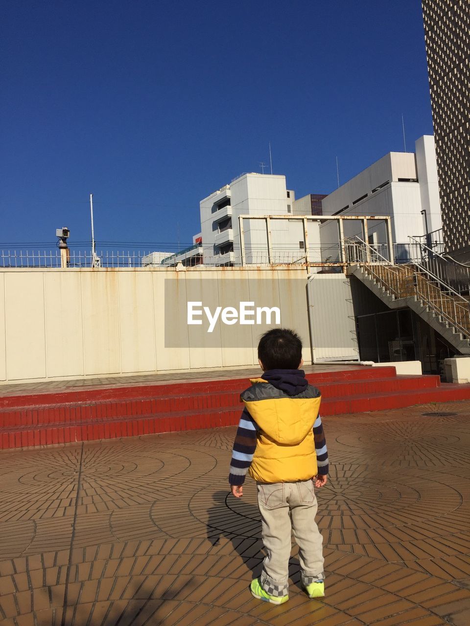 Rear view full length of boy standing against building