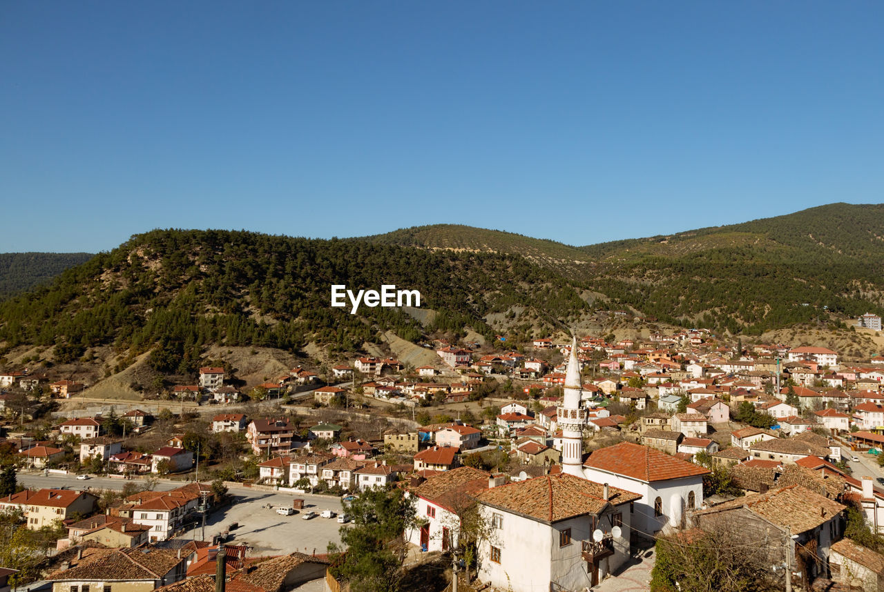 Houses in town against clear blue sky