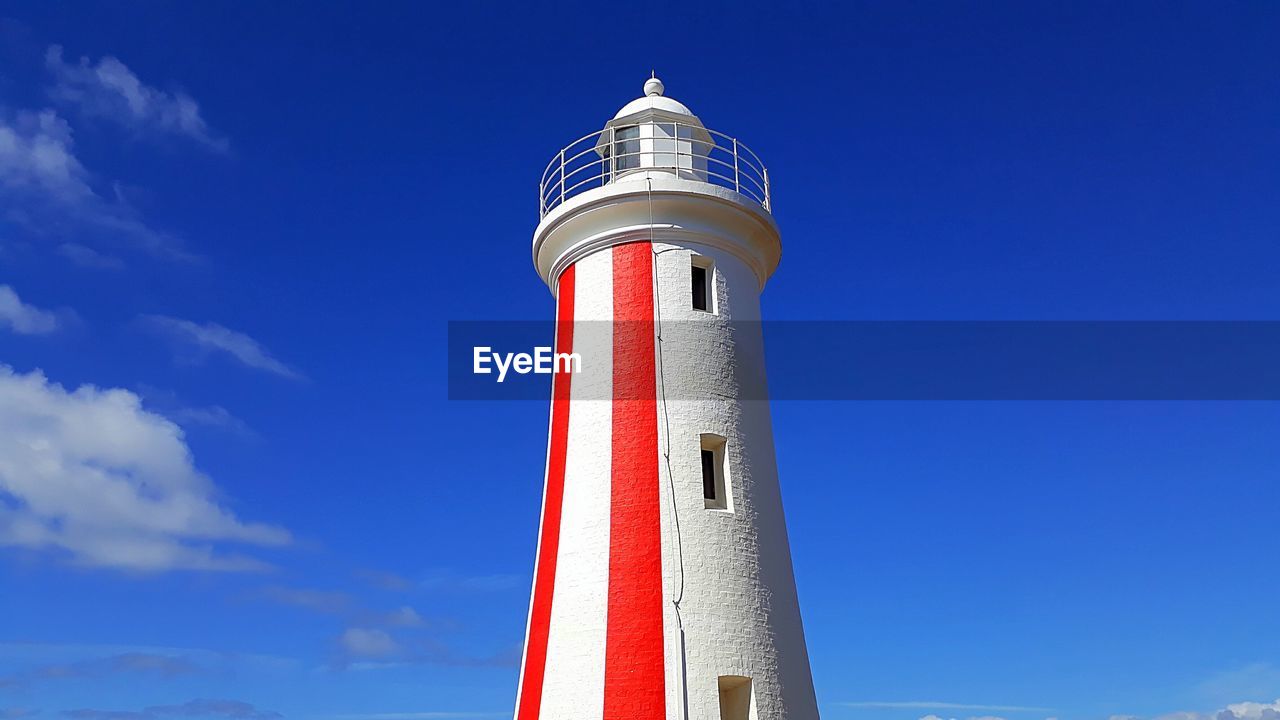 Low angle view of lighthouse by building against sky