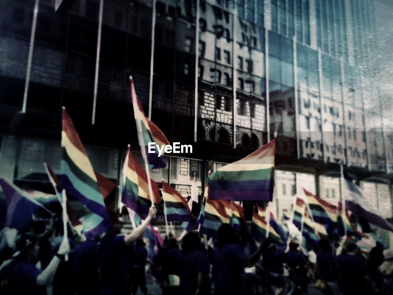 People holding rainbow flags during gay pride parade in city at night