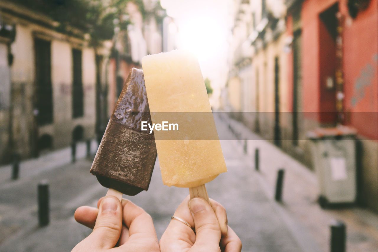 Cropped hands holding ice cream on street