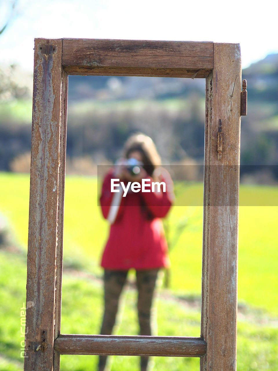 Woman with camera seen through window frame