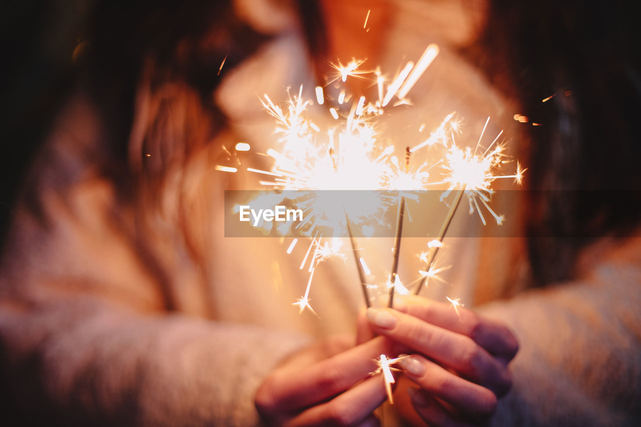 Female hands holding sparklers during christmas in city