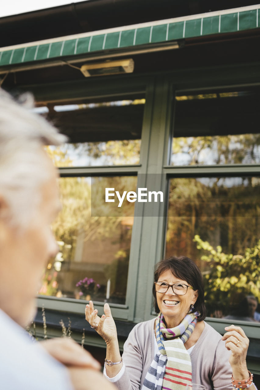 Smiling senior woman gesturing at outdoor cafe