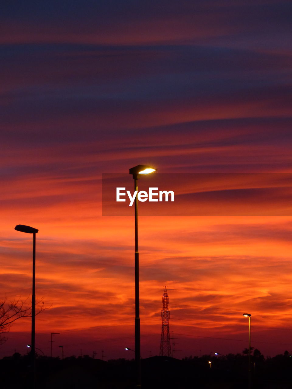 ILLUMINATED STREET LIGHT AGAINST SKY AT SUNSET