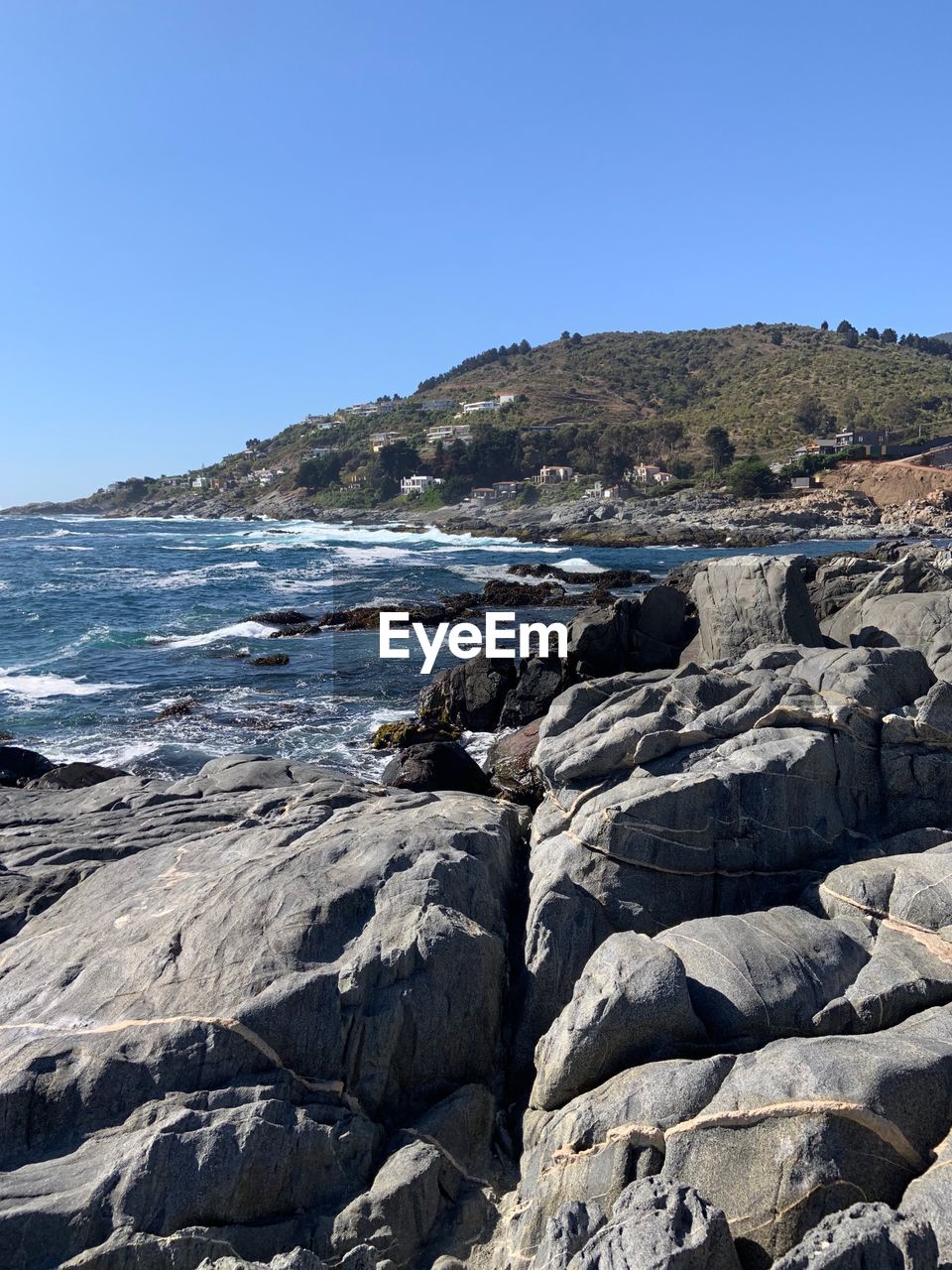 Rocks on beach against clear blue sky