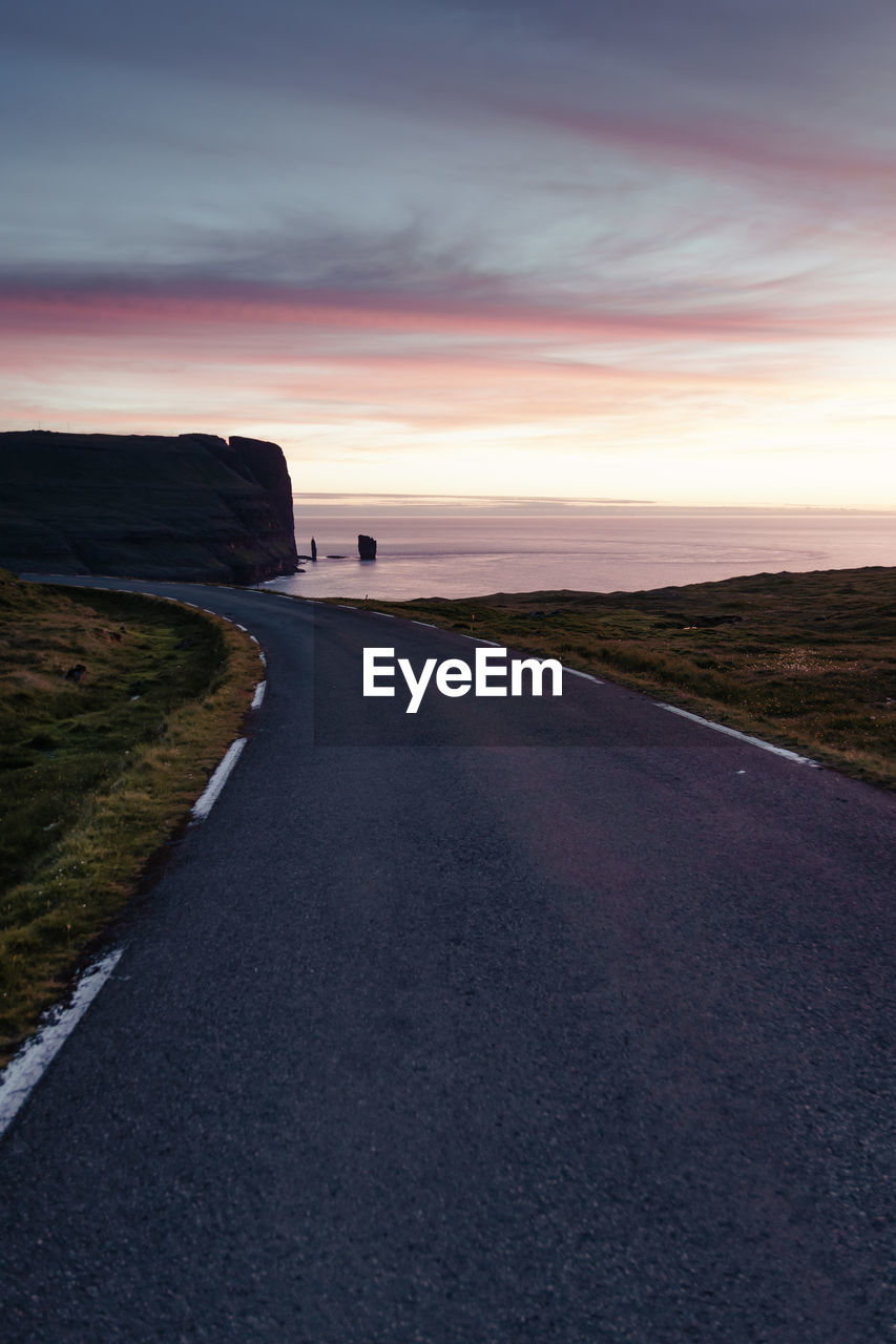 Road by sea against sky during sunset